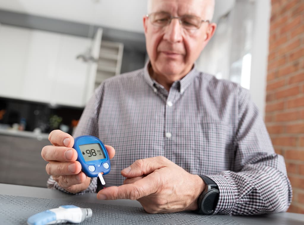 Man with chronic disease testing blood sugar levels at home